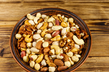 Mixed nuts on wooden table. Walnuts, pistachio, almond, peanut, cashew, hazelnut in ceramic bowl. Healthy eating concept