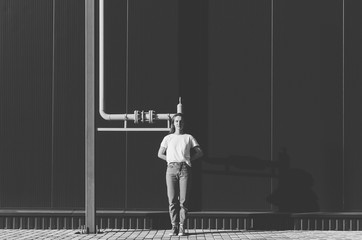 Fototapeta na wymiar Black and white shot of Beautiful Woman in white shirt and jeans against black wall and yellow gas pipe