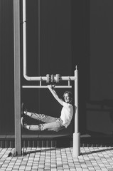 Black and white shot of Beautiful Woman in white shirt and jeans have fun near black wall and yellow gas pipe