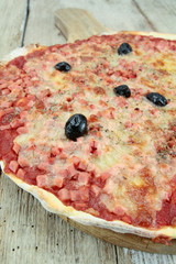 pizza with ham and mozzarella on a wooden table