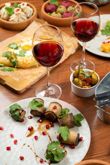 Traditional georgian snack pkhali rolled into eggplant slices on the table with other georgian food and wine