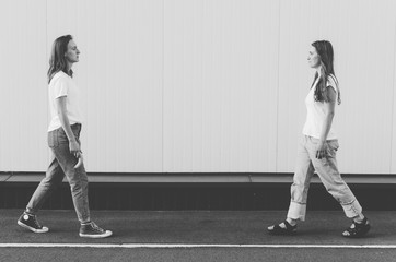 Black and white shot of Beautiful Women in white shirt and jeans holding banana like gun neare white wall