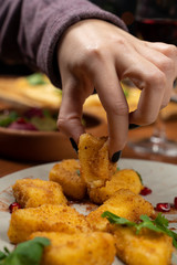 Woman eating deep fried cheese nuggets with hands close up