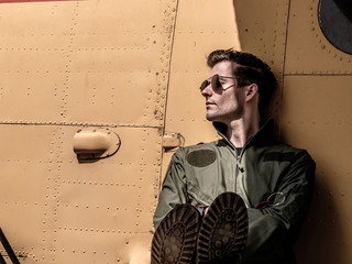 A handsome young pilot sitting on the wing of a plane © nordantin