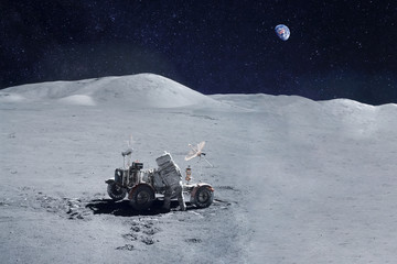 Astronaut near the moon rover on the moon. With land on the horizon. Elements of this image were...