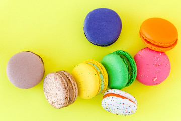 Sweet colorful French macaroon biscuits on pastel yellow background