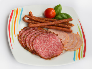Food plat with delicious salami, pieces of sliced ham, sausage, tomatoes and salad  - Meat platter with selection, isolated on a white  background
