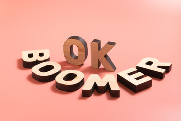 OK Boomer. Internet meme popular among young people. Wooden letters on pink background.