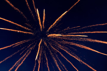 The isolated burst of firecracker sky shot in the dark black night background during the festival of Deepawali resulted in scattering of orange yellow sparkling light rays