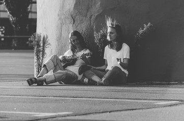 Black and white shot of Young women playing ukulele and sing song on the street