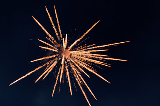 The isolated burst of firecracker sky shot in the dark black night background during the festival of Deepawali resulted in scattering of orange yellow sparkling light rays - Powered by Adobe