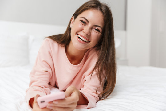 Cheerful lovely young girl wearing pajamas laying in bed