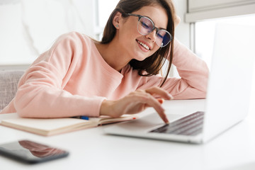Obraz na płótnie Canvas Smiling prettty girl working on laptop computer