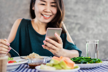 Asian woman using mobile phone while eating dinner at home,internet, social media addiction concept 