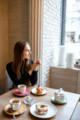 Young woman student sits in a cafe and enjoys a delicious meal.
