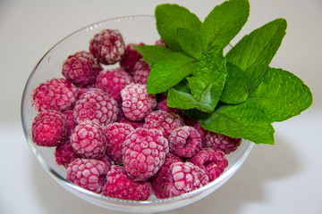 frozen raspberries with mint leaves on a white background