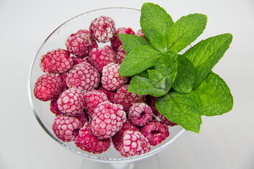 frozen raspberries with mint leaves on a white background