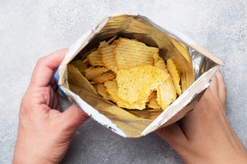 Potato chips with spicy in an open package hold hands. Close up Selective focus.