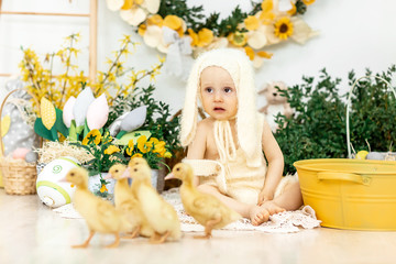 Cute smiling baby in bunny costume in colored Easter decorations, Easter concept