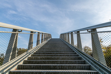 Stairs of a steel high bridge seen from below wit a blue sky