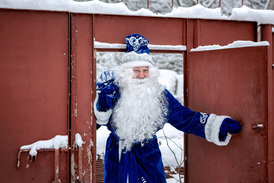 Father Frost enters the gate. Winter day. Santa Claus carries a bag of gifts. Russian Christmas character - Father Frost (Ded Moroz). Christmas Eve.