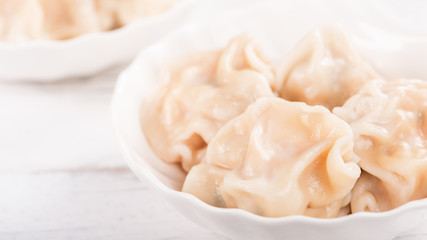 Fresh, delicious boiled pork, shrimp gyoza dumplings on white background with soy sauce and chopsticks, close up, lifestyle. Homemade design concept.