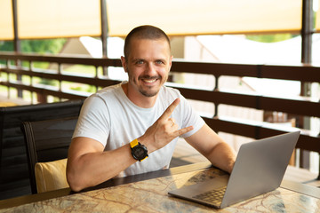 Man showing gesture Rock on sitting at desk with laptop