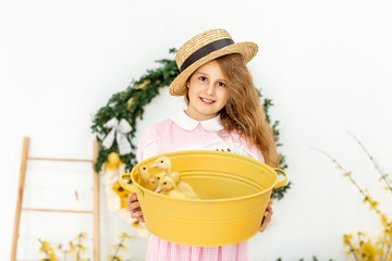 Happy little girl in a straw hat dress and holds cute fluffy ducklings in her hands. Easter greeting card, Easter concept