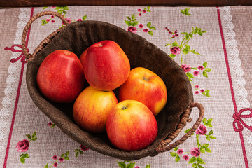 A basket of apples stands on a cloth napkin.