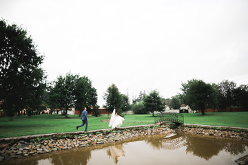 Happy wedding couple. Bride running from groom in a botanical park