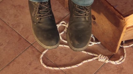 feet of a hanged dead man dangling with the stool and the rope used to hang himself