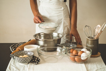 Woman adds some flour to dough on wooden table. Woman hands kneading fresh dough. Concept ingredients for cooking flour products or dough. Rural or rustic style.