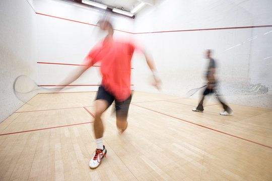 Squash players in action on a squash court (motion blurred image; color toned image)