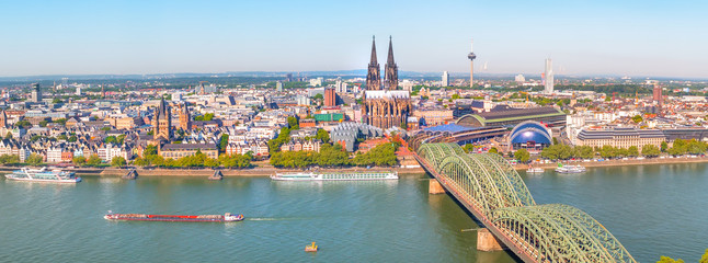 Aerial panorama of the Hohenzollern bridge over Rhine river on a sunny day. Beautiful cityscape of Cologne, Germany  with cathedral and Great St. Martin Church in the background - obrazy, fototapety, plakaty