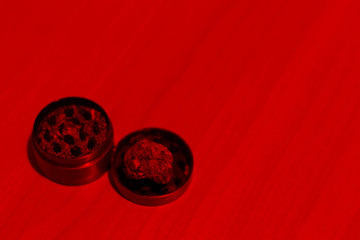 Medical marijuana in a grinder on a table in dark red lighting. Drug use for medical purposes. Copy space