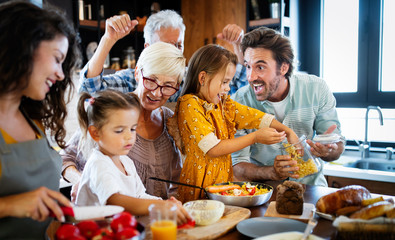 Grandparents, parents and children spending happy time in the kitchen