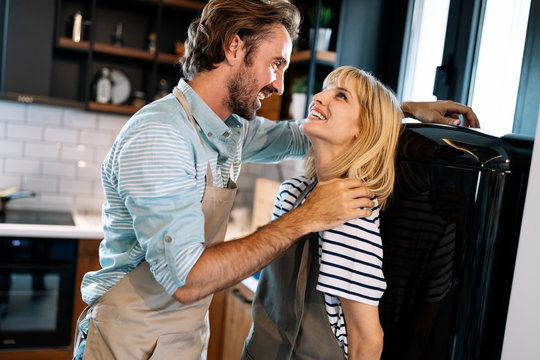 Spontaneous romantic couple making love in kitchen while preparing food