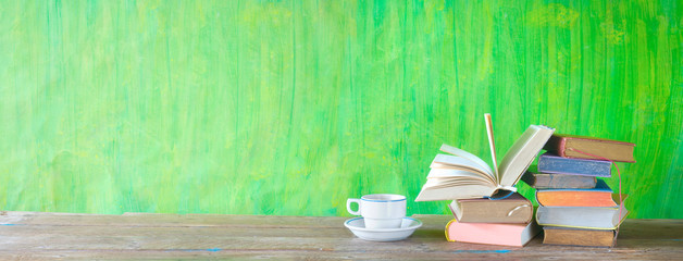 Open Book and stack of multicolored hardback books with a cup of coffee, reading education,...