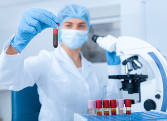 Young female scientist holding tube with blood sample