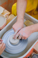 male hands forming clay on pottery wheel