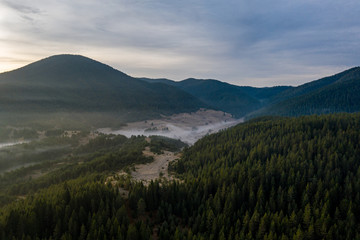 Beautiful sunrise in the mountains with fog crawling between the trees and houses in a village