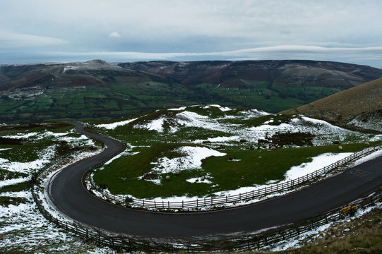 A view of the road across Sheepfold towards Rushup Edge in the Peak District with a covering of snow, from Maam Tor