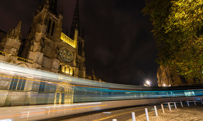 Tram passing Bordeaux Cathedral at night in Gironde in New Aquitaine, France