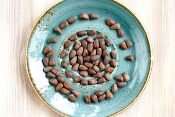 Pine nuts on blue plate on wooden background. Healthy eating, organic food concept.