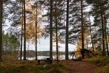Windshield shelter by a calm lake with mirror reflections inside a forest during autumn in Sweden. 