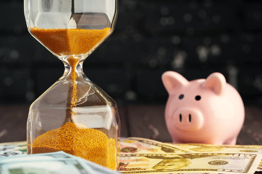 Time and money business concept. Sandglass and money