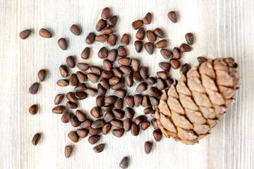 Pine cone and nuts on light wooden background. Healthy eating, organic food, vegetarian concept.