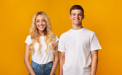 Portrait of smiling millennial guy and girl over yellow background
