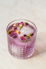 Pink Gin Tonic Cocktail with Dried Rose Buds and Ice in Glass Cup