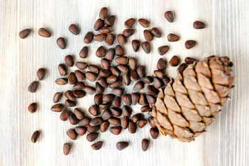 Pine cone and nuts on light wooden background. Healthy eating, organic food, vegetarian concept.
